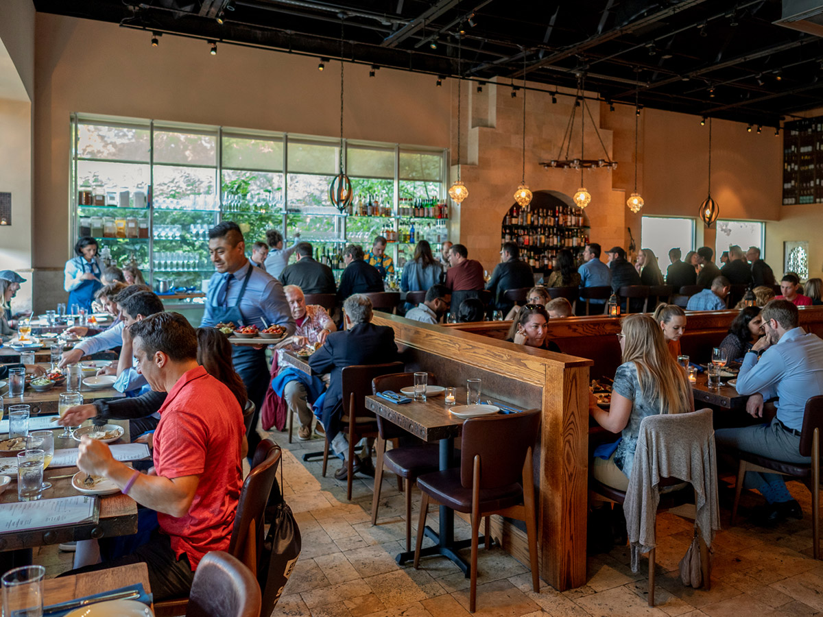 The bustling dining room at Zahav features rustic tables, bar seating and a chef's counter.