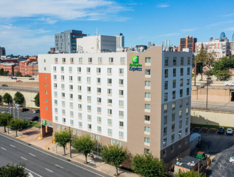 Toma aérea del exterior del Holiday Inn Express en Penn's Landing, un cielo azul, el horizonte de Filadelfia y un aparcamiento se ven en el fondo