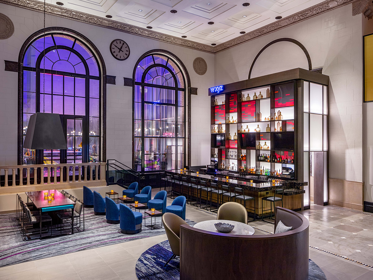 The sleek and stylish lobby bar at the Aloft Philadelphia Downtown, with large windows and colorful furniture