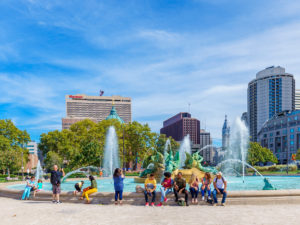 Mensen zitten op een mooie dag in Philadelphia op de rand van een fontein in Logan Square.