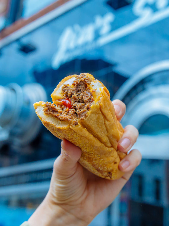 A cheesesteak hoisted triumphantly in front of Jim's Steaks in Philadelphia