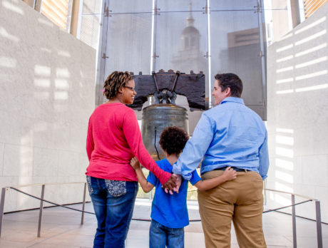 A couple and a child stand in front of the Liberty Bell in Philadelphia