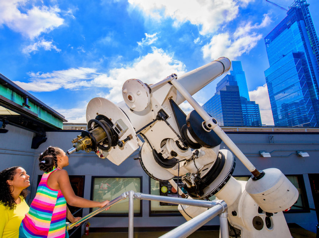 Girl looking through telescope at The Franklin Institute