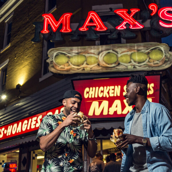 Two people enjoying cheesesteaks at Max's.