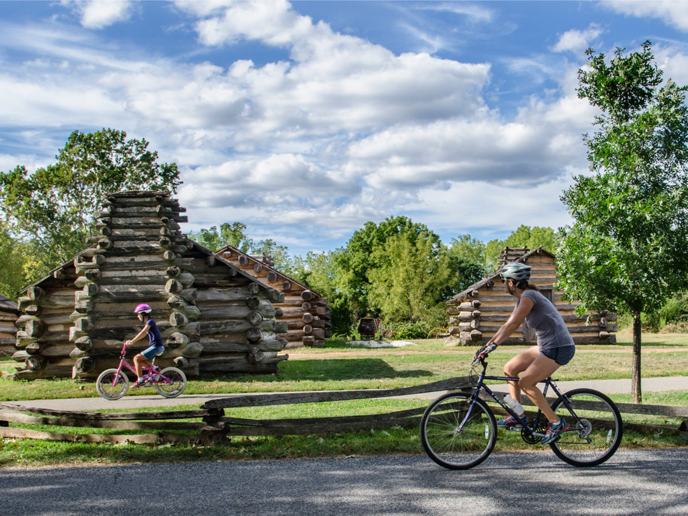 Bikers ride past reconstructed cabins in Valley Forge National Historical Park