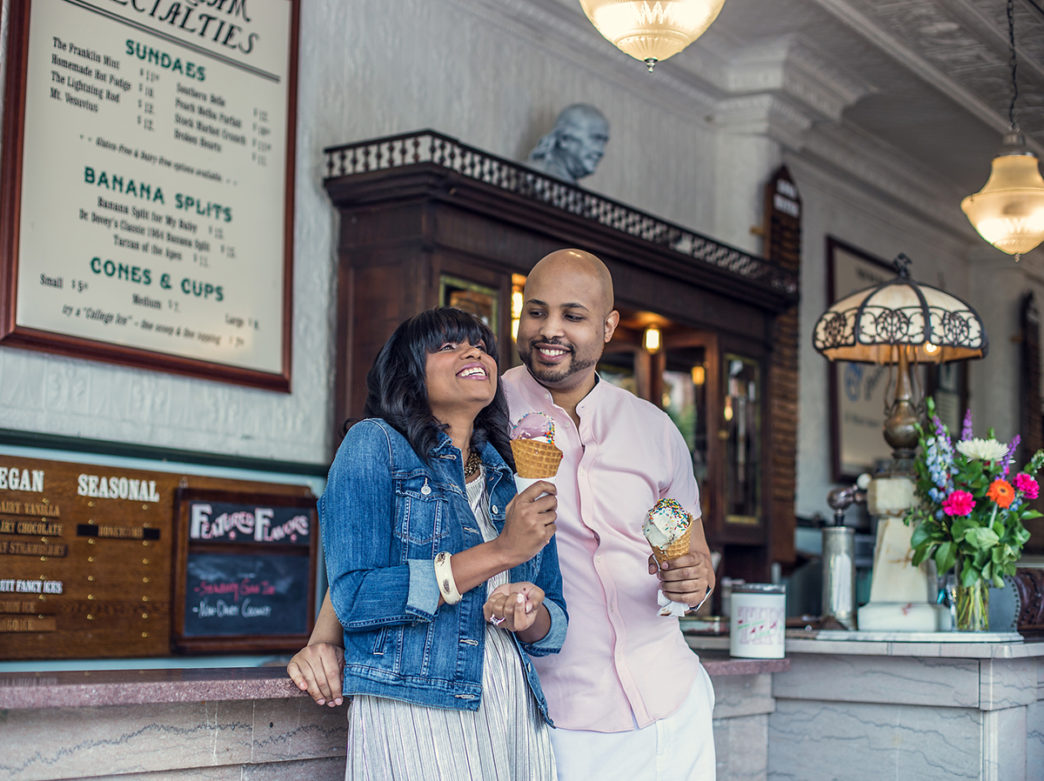A couple laughs as they eat ice cream in waffle cones at The Franklin Fountain