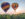 Two colorful hot air balloons float above trees as the sun rises.