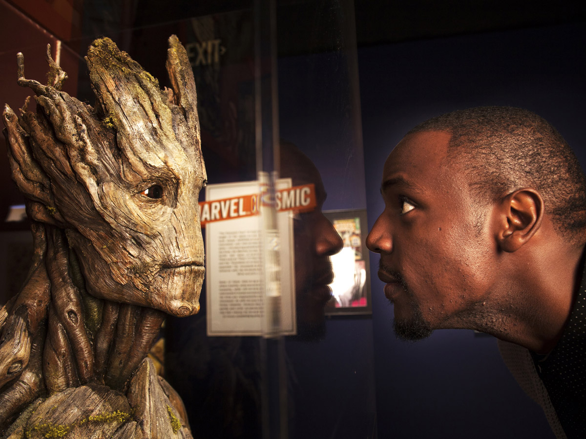 A man looking at Groot in a Marvel exhibit