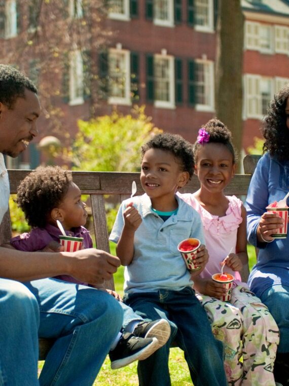A family of five enjoys cups of water ice on a bench in Washington Square