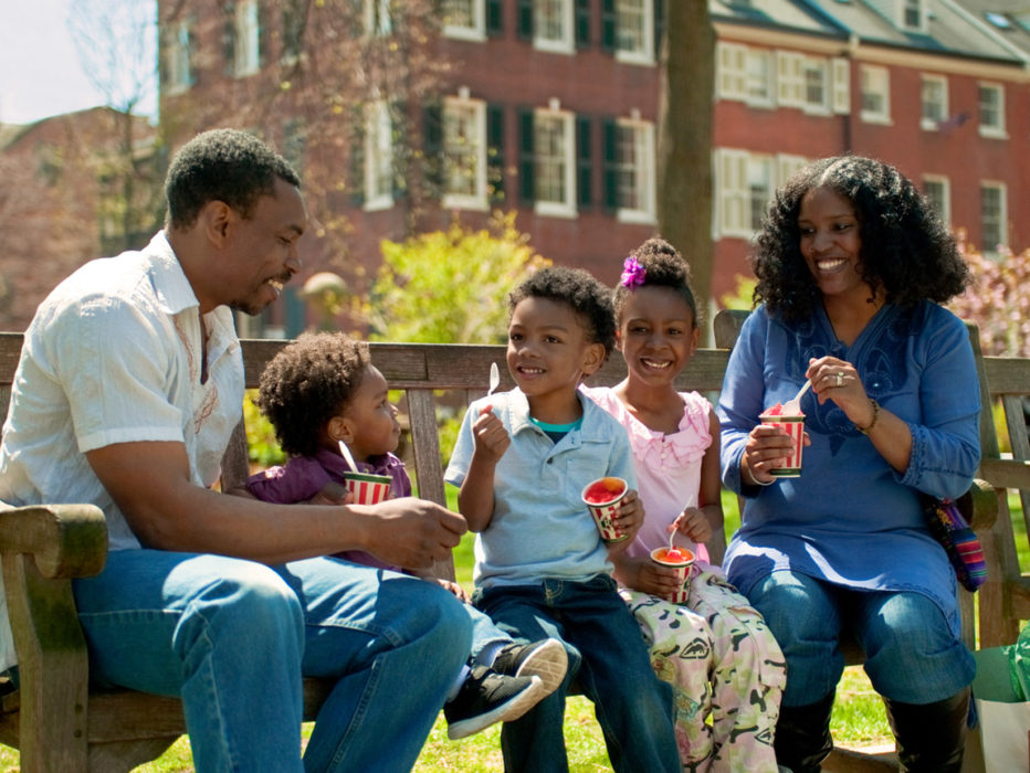 A family of five enjoys cups of water ice on a bench in Washington Square