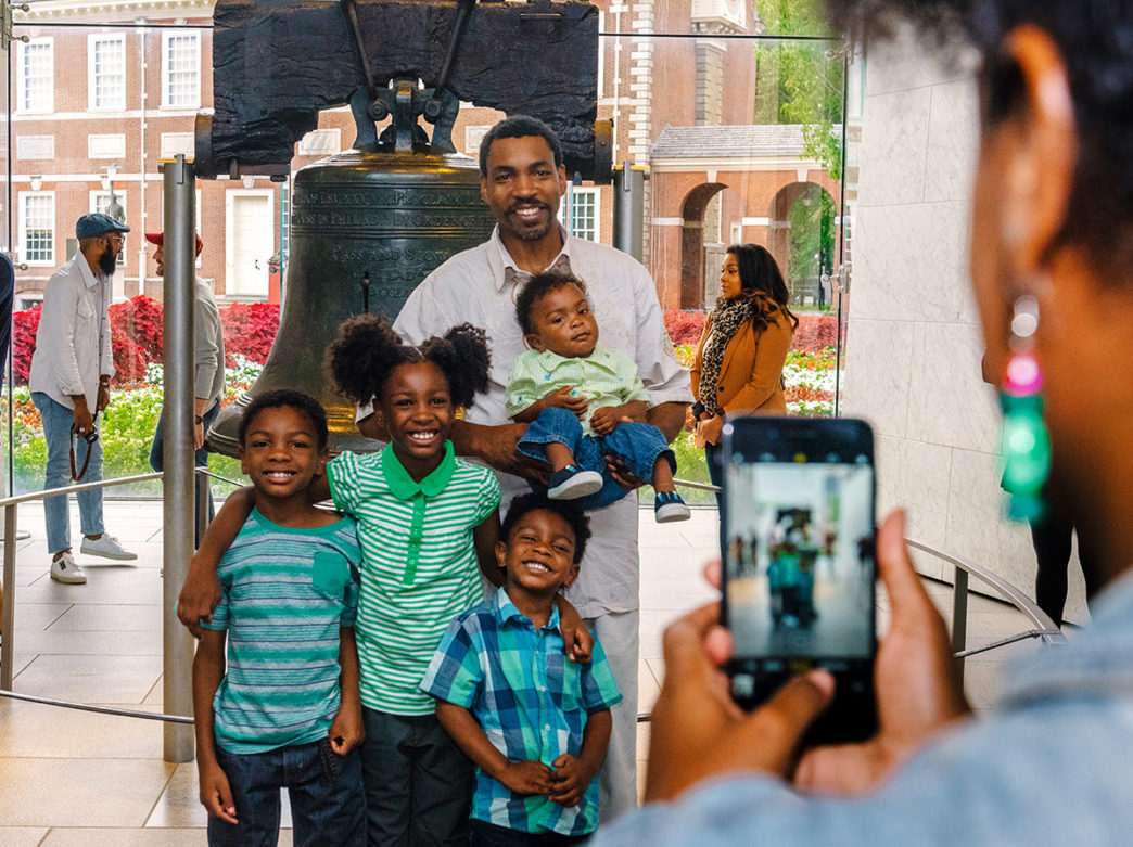 Family posing for a photo with the Liberty Bell in Philadelphia
