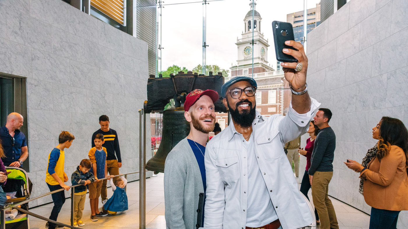 Couple posing for a selfie with the Liberty Bell in Philadelphia