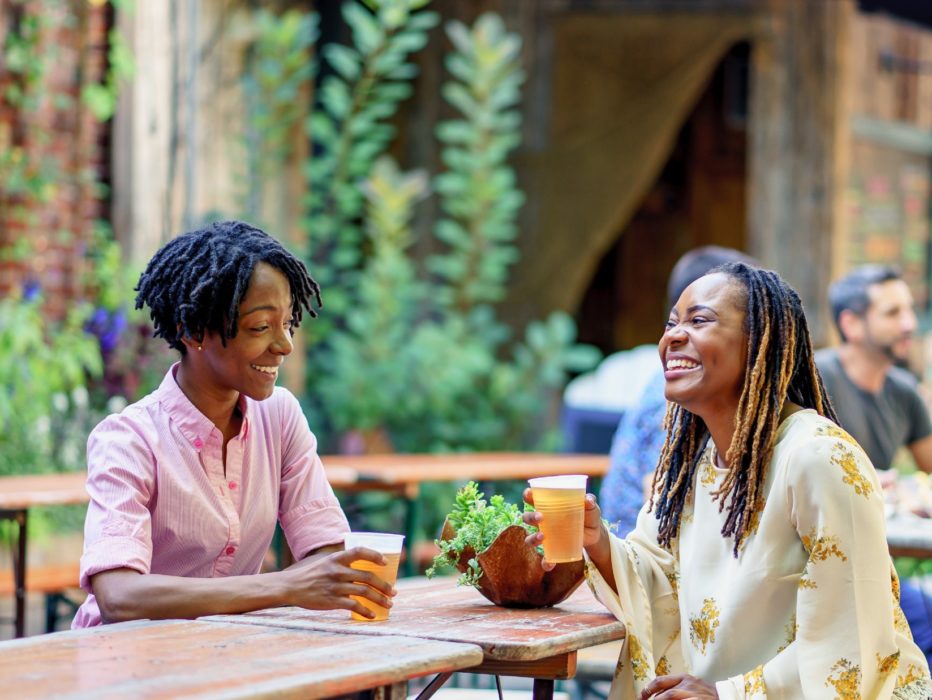Two women enjoy a beer and laugh at PHS Pop Up Garden at South Street in Philadelphia