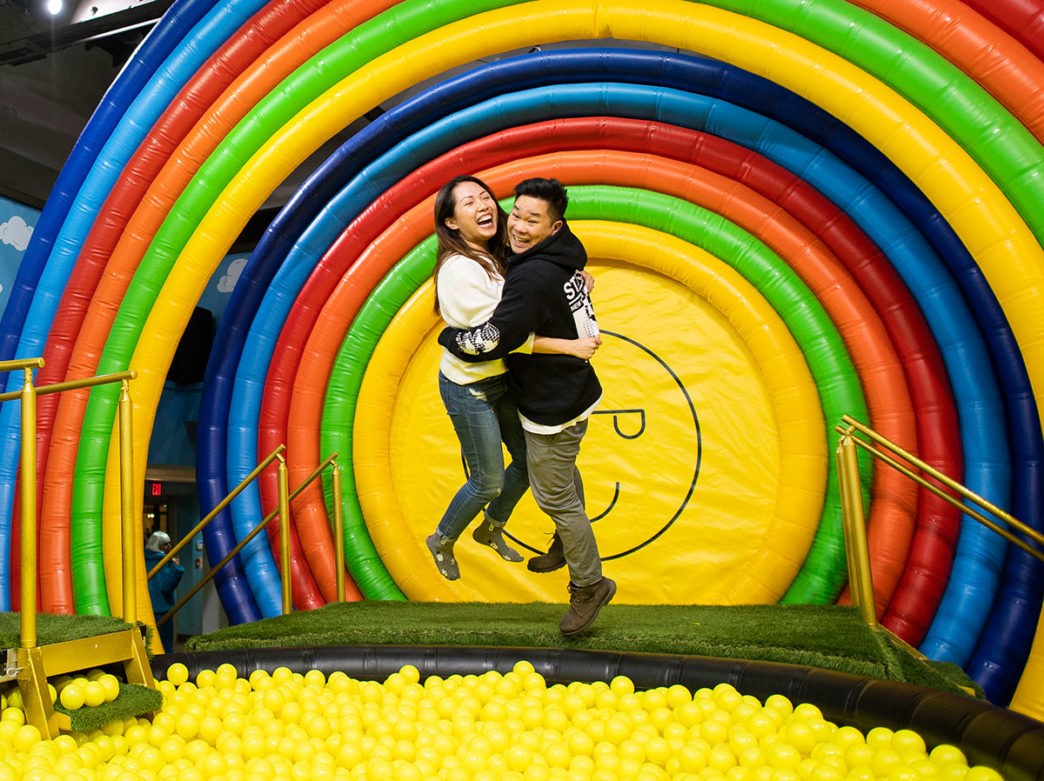 Couple jumping into the Happy Place ball pit at the King of Prussia Mall