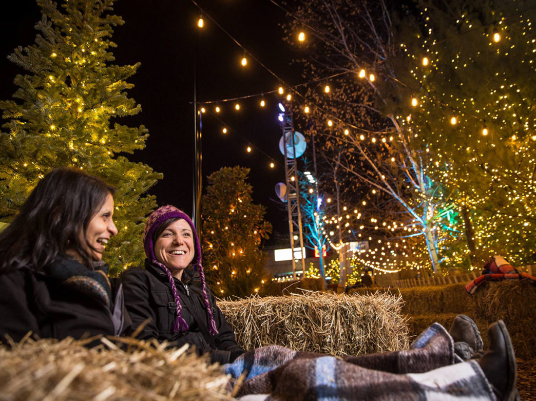 Two guests at Blue Cross RiverRink Winterfest sitting around holiday lights