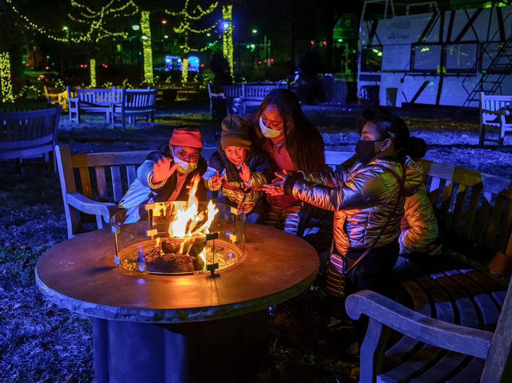 A family sits around a fire pit at Franklin Square in Philadelphia