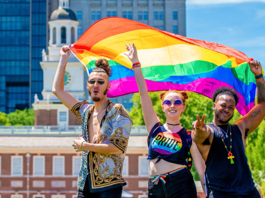 Des personnes avec un drapeau de la Fierté devant le Independence Hall à Philadelphie