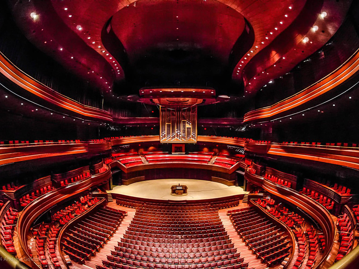 Het interieur van de Marian Anderson Hall in het Kimmel Center, met gebogen rijen rode stoelen rondom het podium en de orgelpijpen.