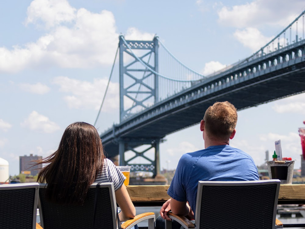 Two people sitting outside at Morgan's Pier on the Delaware River waterfront in Philadelphia