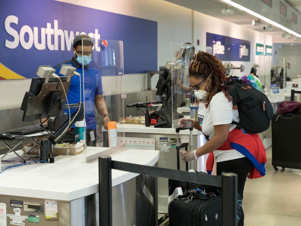 Plastic barriers and masks go into the new check-in procedure at the Philadelphia International Airport