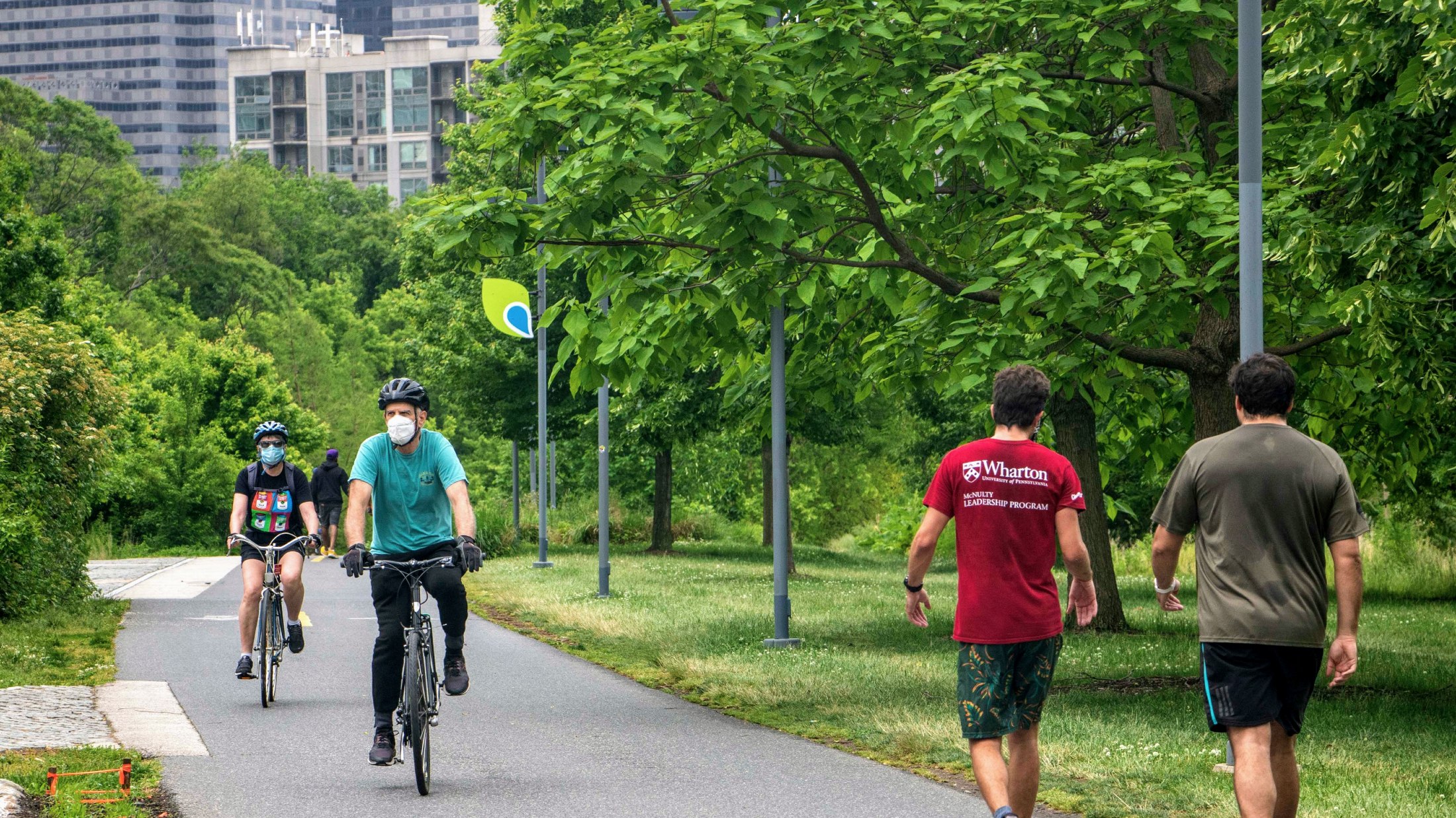 Two bike riders with masks on ride on the Schuylkill River Trail in Philadelphia