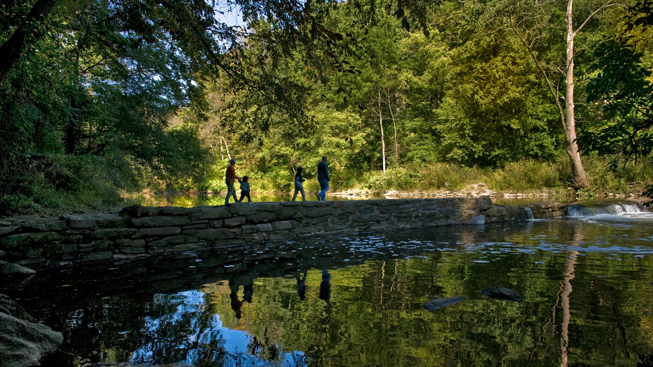 People walk on a wall over Wissahickon Creek in Philadelphia
