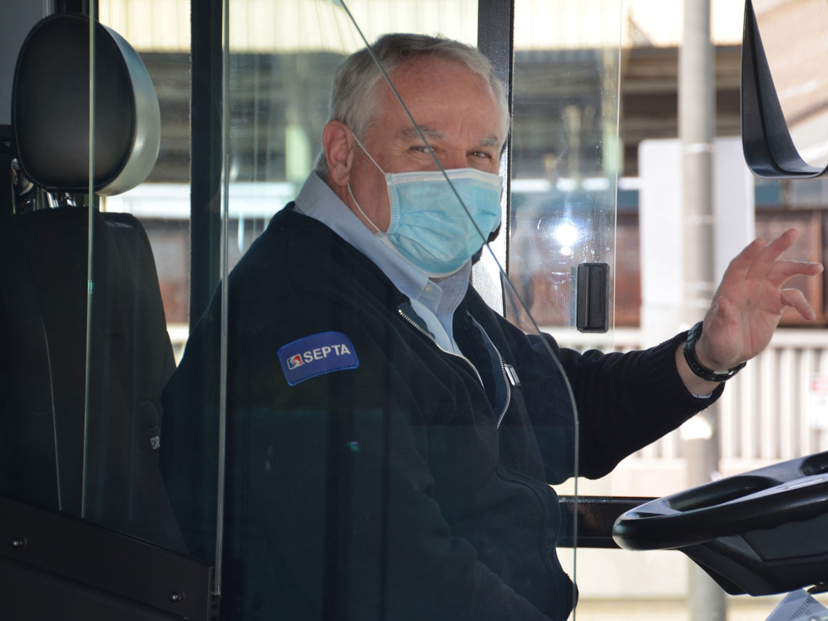 A SEPTA bus driver wears a mask for safety as he waves to passengers coming aboard