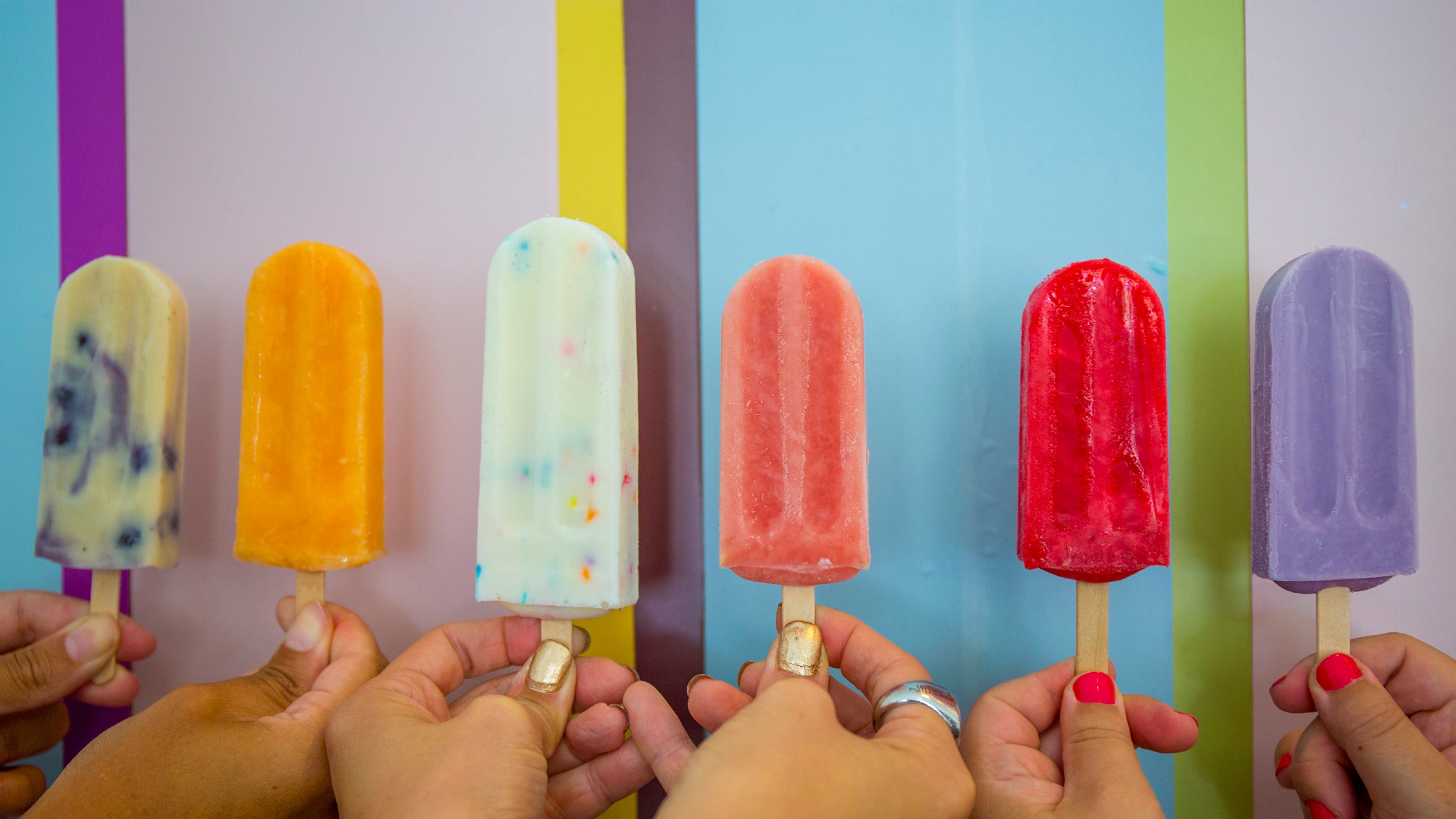 Colorful popsicles held by multiple people at Lil Pop Shop in Philadelphia