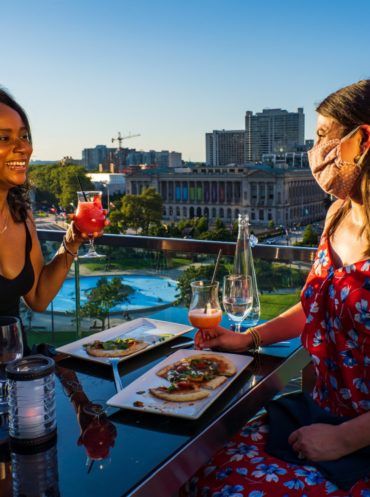 Two people drink and dine at the Rooftop Assembly Lounge in Philadelphia