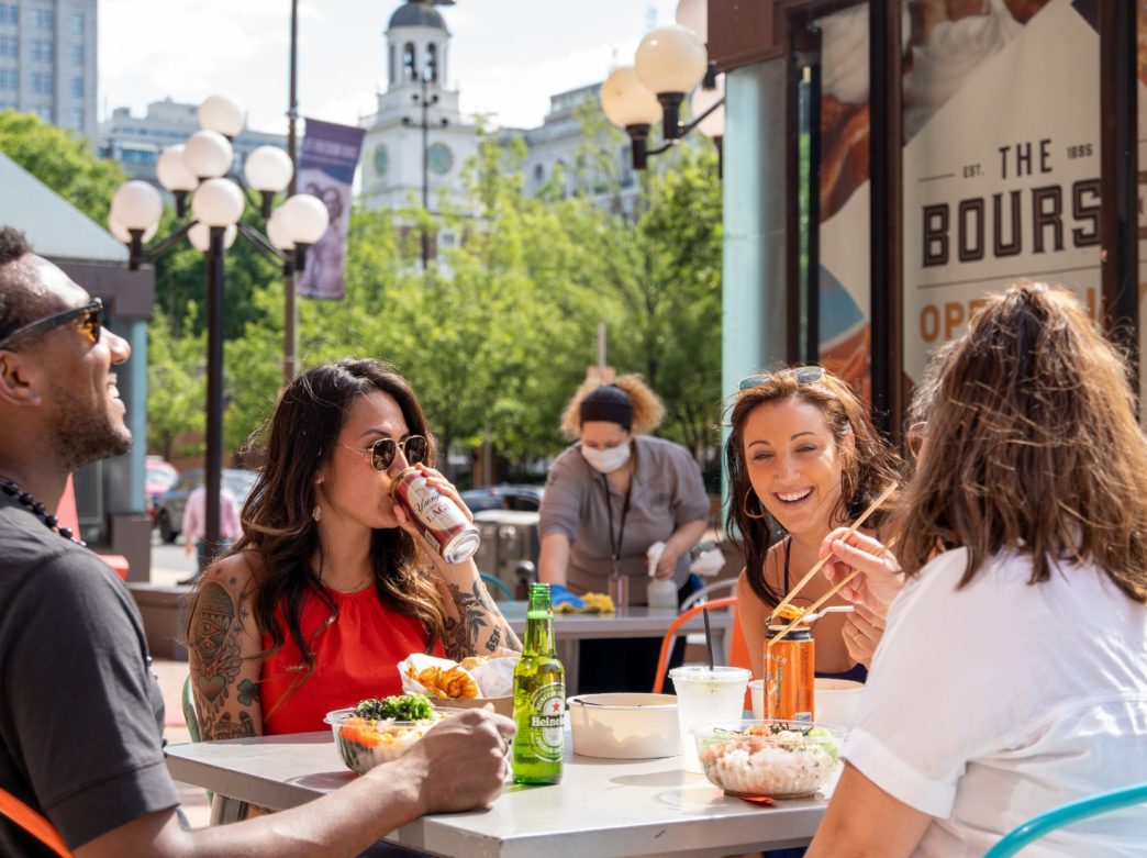 People dine outdoors outside of The Bourse Food Hall in Philadelphia