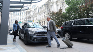 Two people get out of their car in Philadelphia in the shadow of City Hall