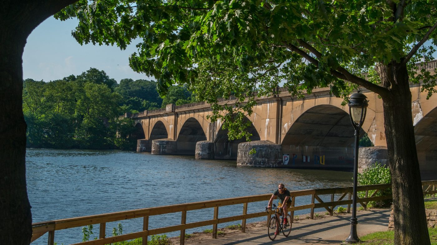 A person riding their bike on Kelly Drive with the river in the background