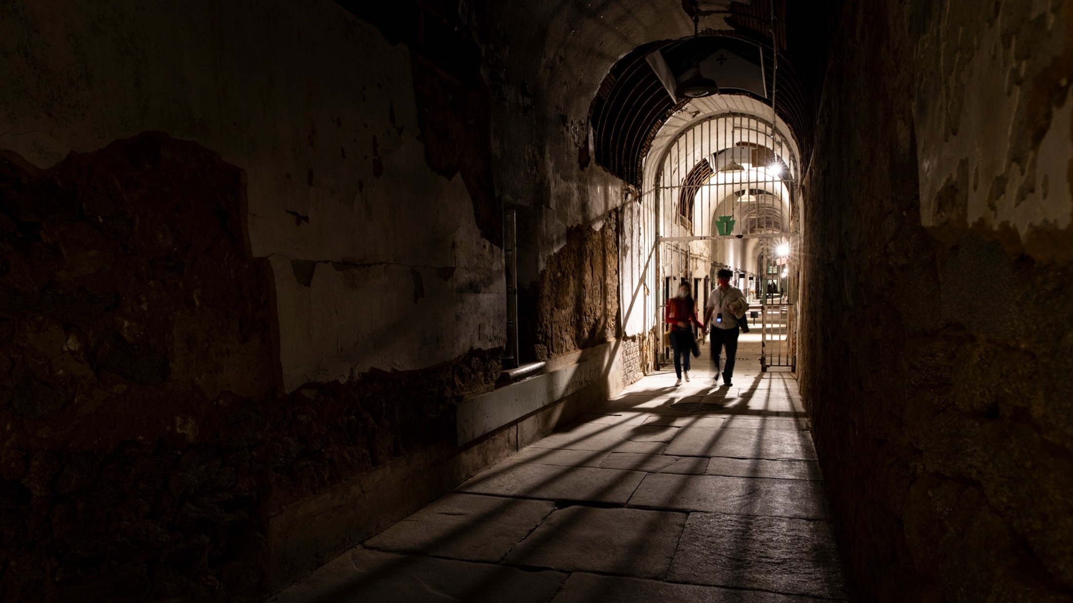 Two people explore Eastern State Penitentiary at night in Philadelphia