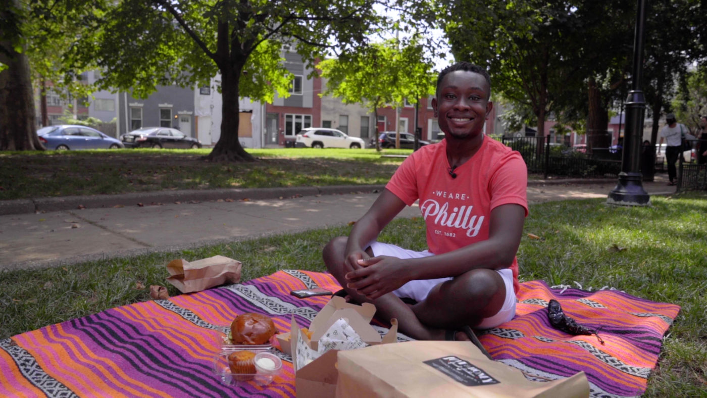Instagrammer Josh Eats Philly wears a red shirt as he enjoys a picnic of fried chicken in Palmer Park in Philadelphia's Fishtown neighborhood.