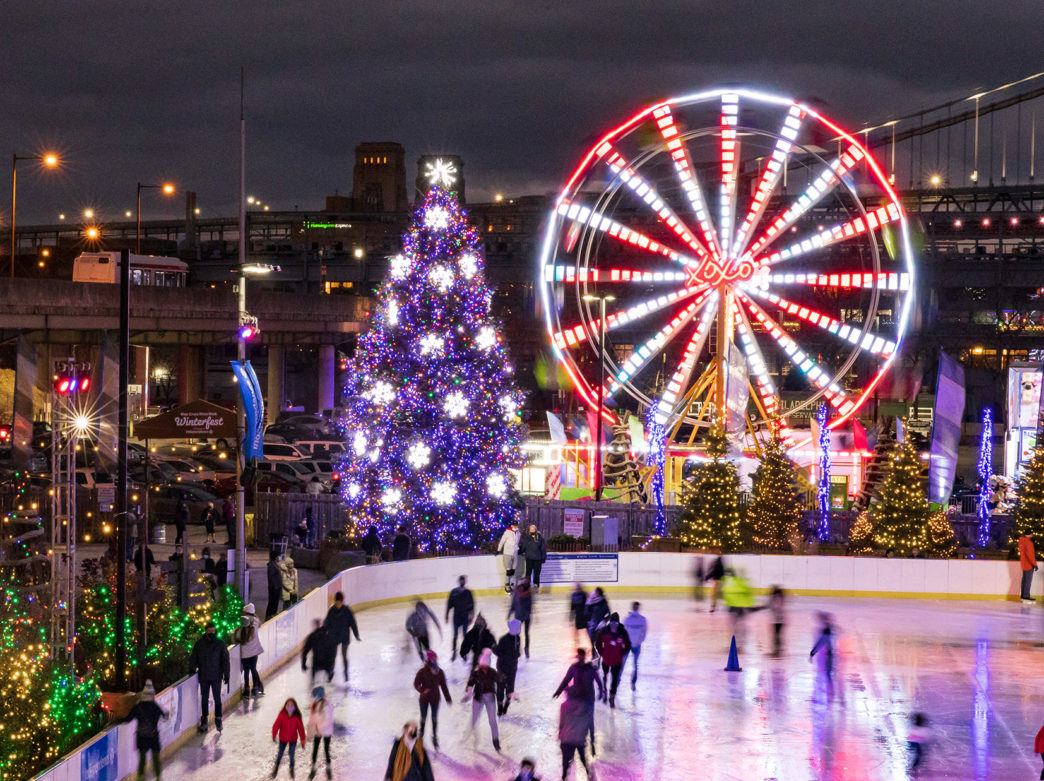 People wearing masks ice skate at Blue Cross RiverRink Winterfest in Philadelphia