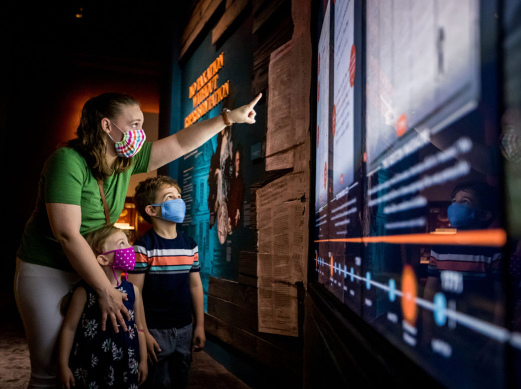 A mom and two young children wearing covid masks check out the Museum of the American Revolution in Philadelphia