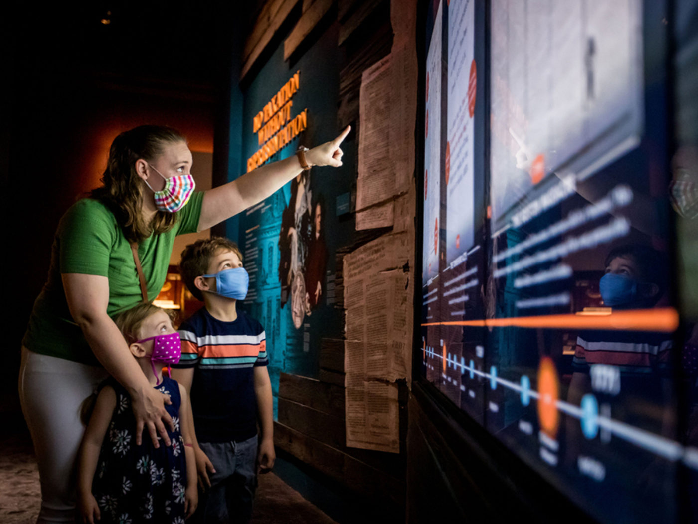 Una madre y dos niños pequeños con máscaras covídeas observan el Museum of the American Revolution en Filadelfia