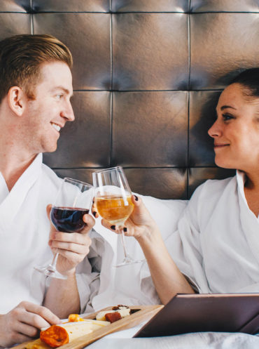 A couple in bed at a hotel and eats room service