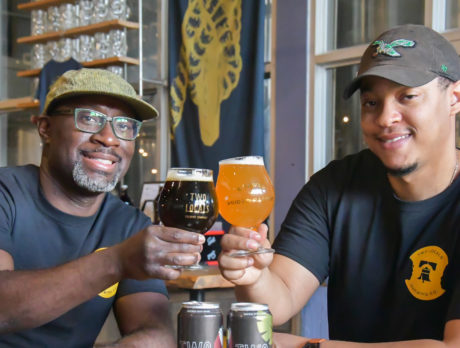 Owners and brewers of Two Locals toast with beer glasses in hand