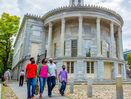 A family wearing masks walks past the Merchants Exchange building in Old City Philadelphia