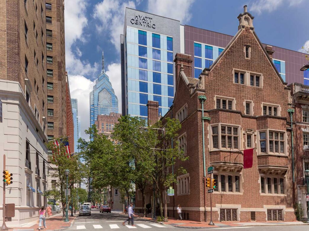 Hyatt Centric hotel rises above surrounding buildings in Philadelphia’s Rittenhouse Square neighborhood, with a modern glass façade set alongside historic brick architecture and the city skyline in the background.