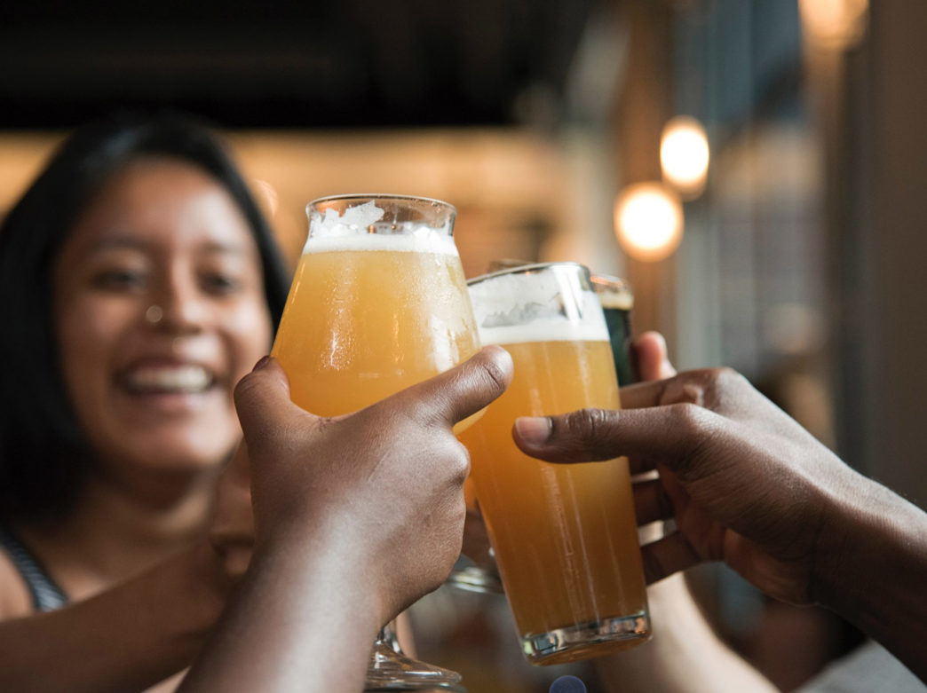 A woman toasts her friends while holding beers at Dock Street Brewery in Philadelphia