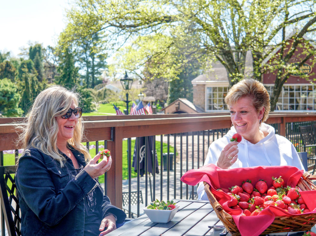 Two women eat strawberries from a basket at Peddler's Village outside Philadelphia