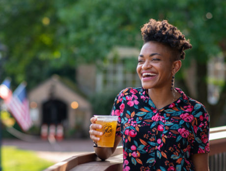 A person smiles and holds a beer at Peddler's Village