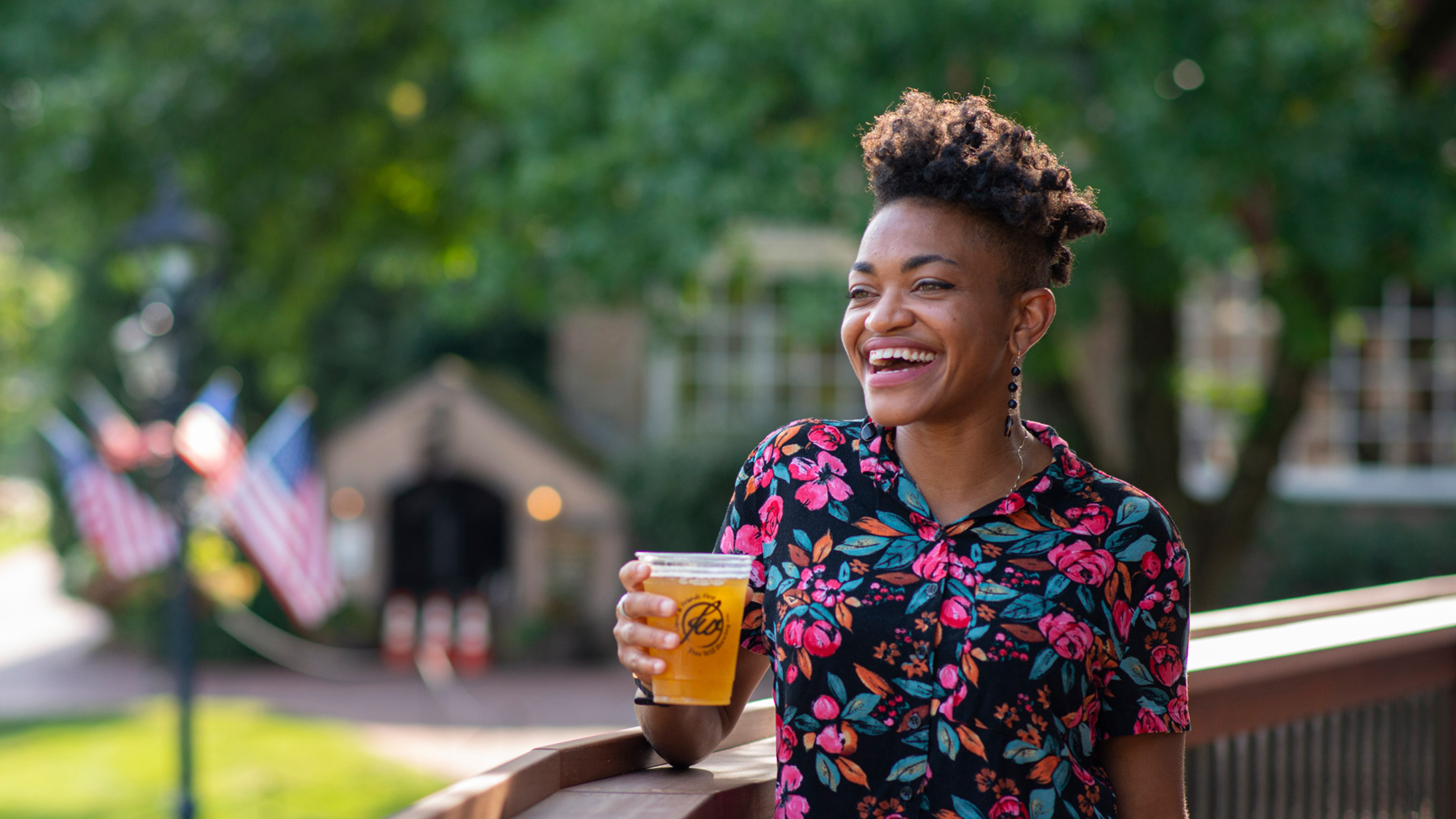 A person smiles and holds a beer at Peddler's Village