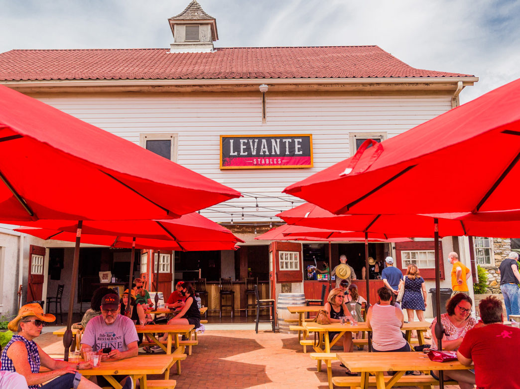 People sit outdoors at tables outside the Levante Stables barn