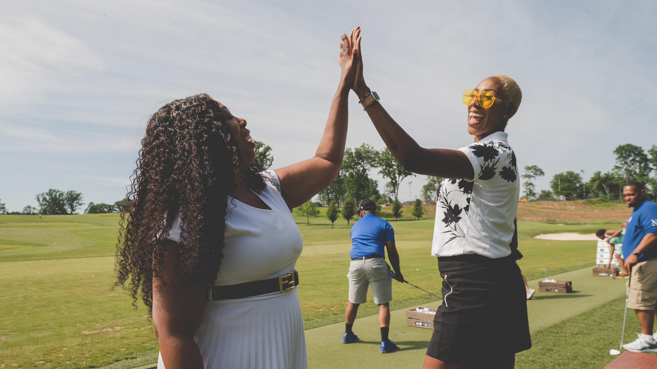 Two people high five during the Visit Philadelphia: Black Greek Edition Golf Outing