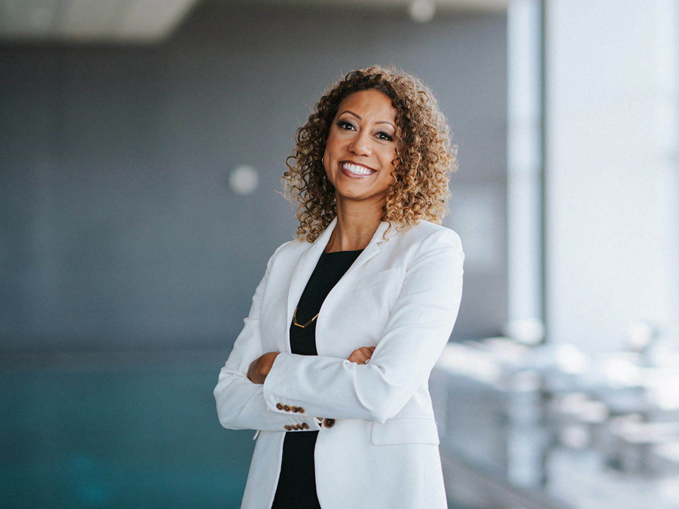 Angela Val, President and CEO of Visit Philadelphia, stands with her arms folded wearing a white jacket