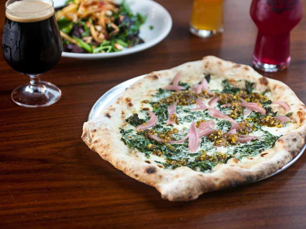 Pizza on a wooden table next to beer at Urban Village Brewing Company in Philadelphia