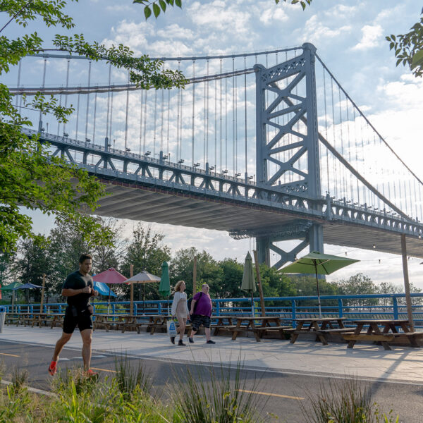 O Benjamin Franklin Bridge fica suspenso no céu enquanto um corredor se move em primeiro plano na Filadélfia.